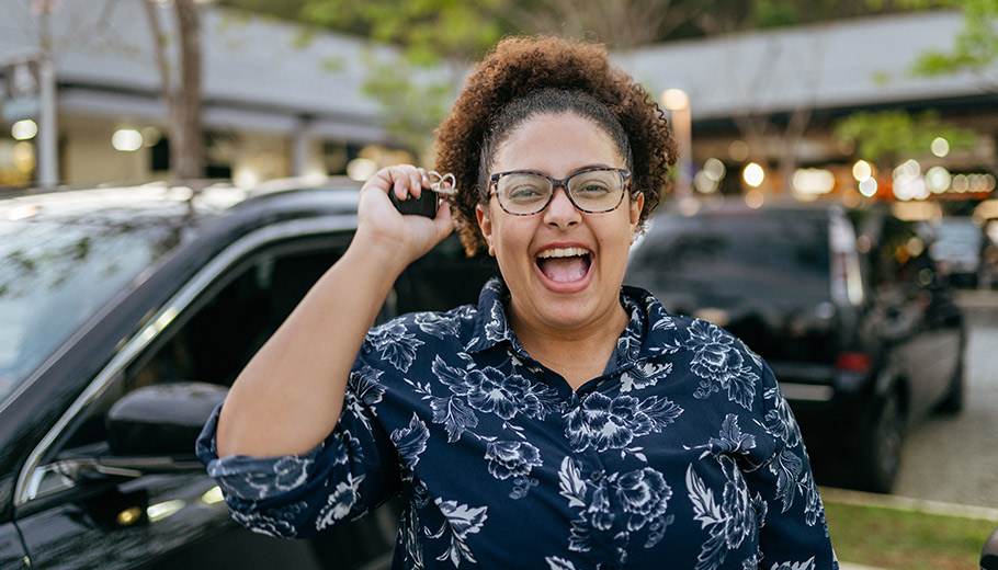 Woman excited about new car holding up keys with an open-mouth smile