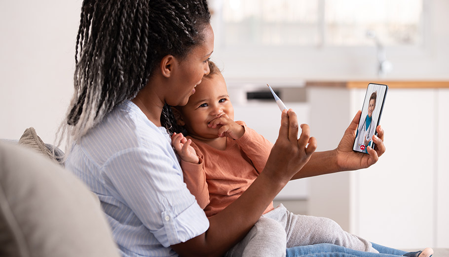 Mother holding thermometer and her baby on a virtual doctor visit 