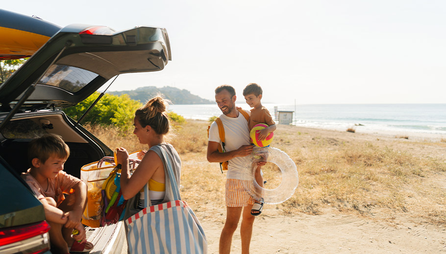 Family of four unpacking their vehicle at the beach