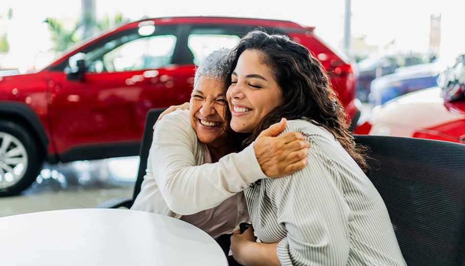 Mother and daughter hugging buying a new car