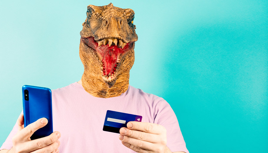 Man wearing a dinosaur mask holding his phone and credit card