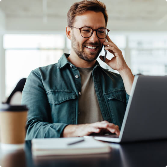 Man on phone while using laptop 