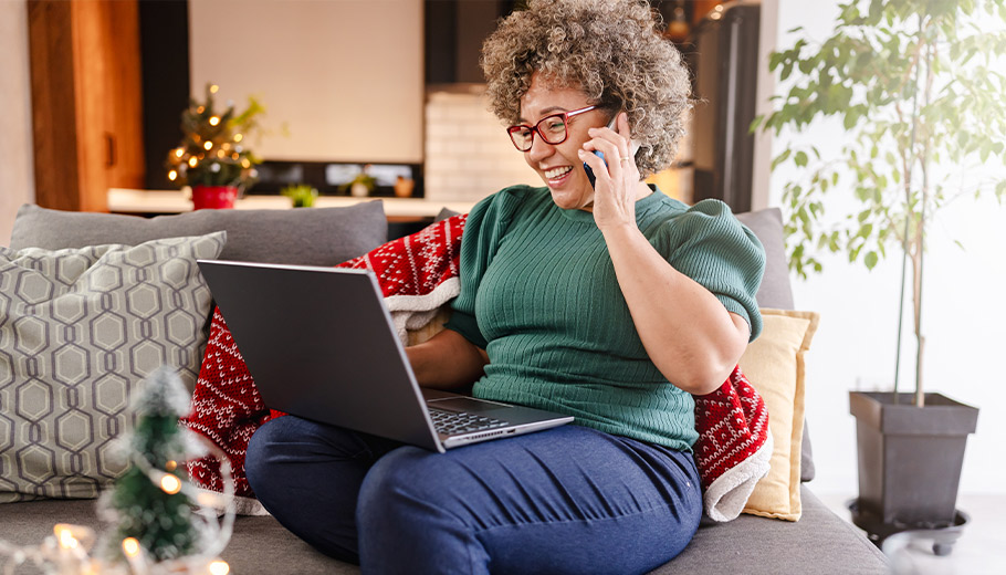 Woman on her phone smiling looking at her laptop