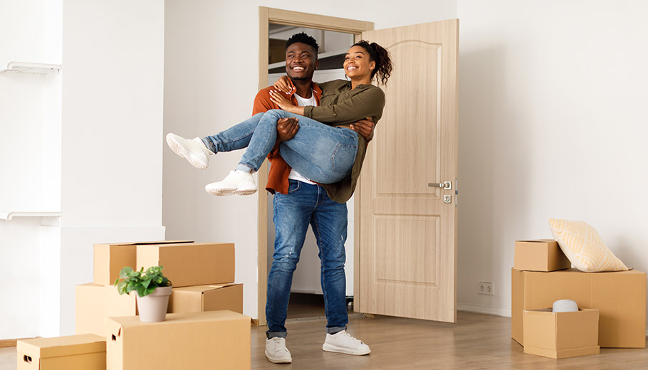 Man carrying woman through door of new home