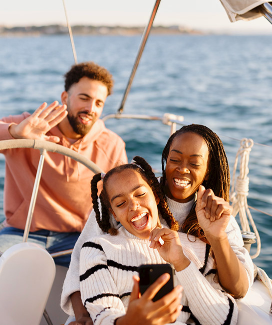 Family on a boat with two parents and preteen daughter smiling taking a selfie