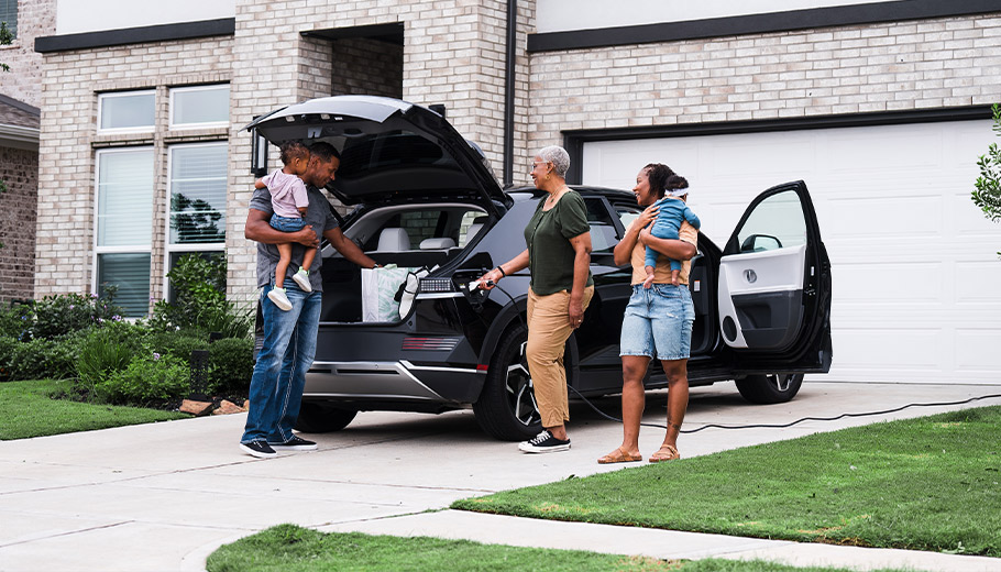 Family with grandmother, parents, and two kids packing trunk of their electric vehicle