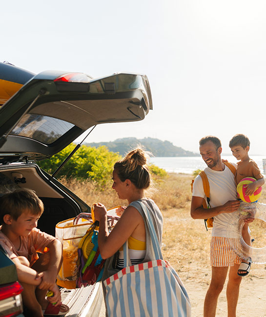 Family of four unpacking their vehicle at the beach