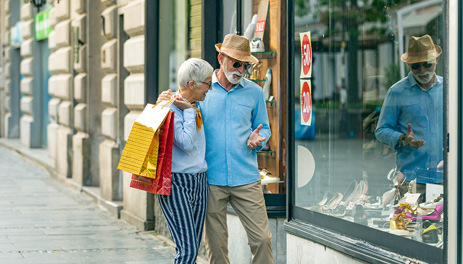 Older couple walking outside stores holding shopping bags
