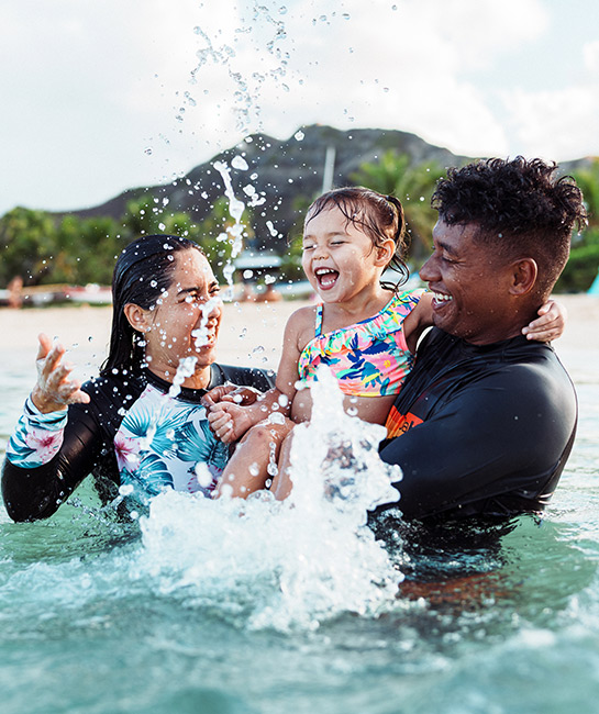 Couple with their baby swimming in the ocean on vacation