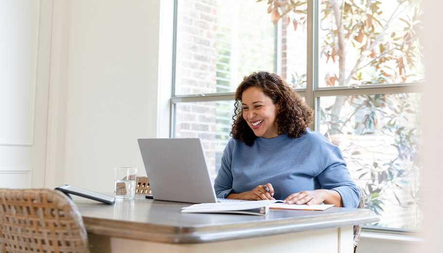 Woman attending seminar online taking notes