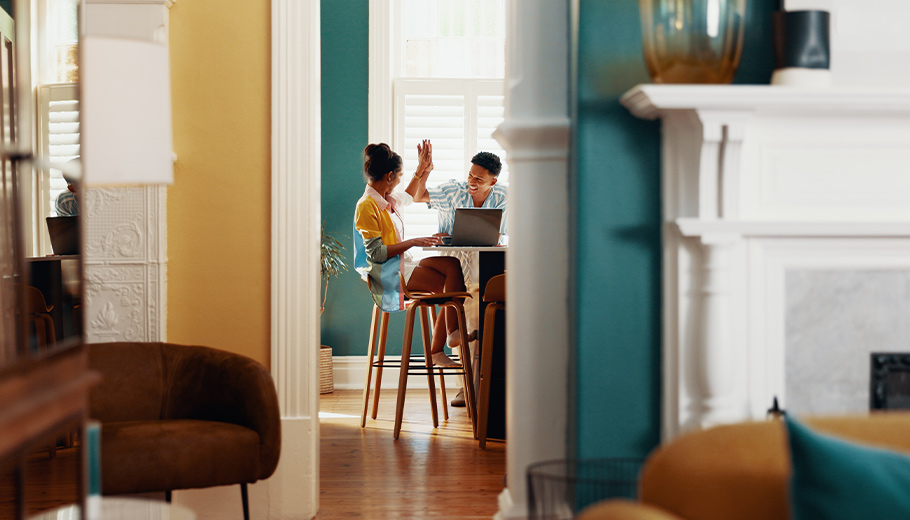 couple high fiving in kitchen with a laptop on the counter