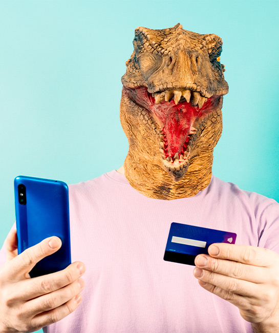 Man wearing a dinosaur mask holding his phone and credit card