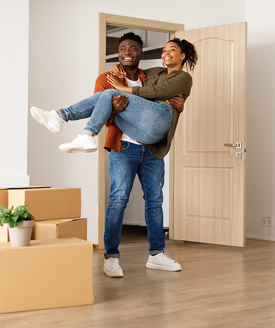 Man carrying woman through door of new home