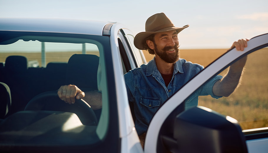 Cowboy smiling in field by his new truck
