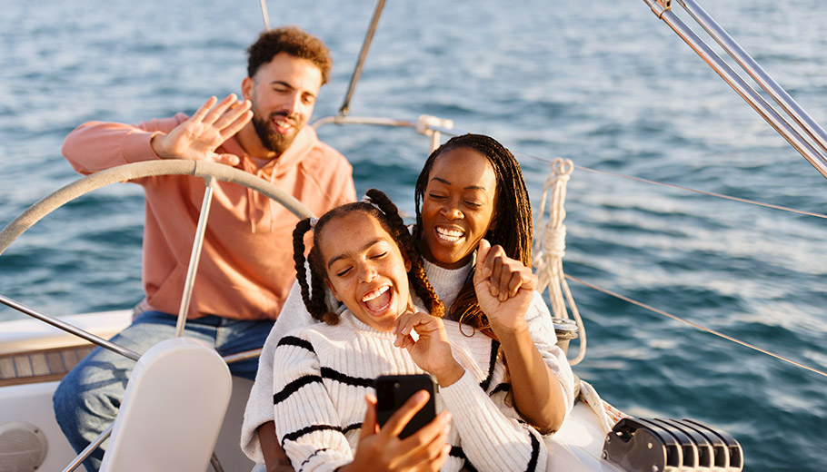 Family on a boat with two parents and preteen daughter smiling taking a selfie