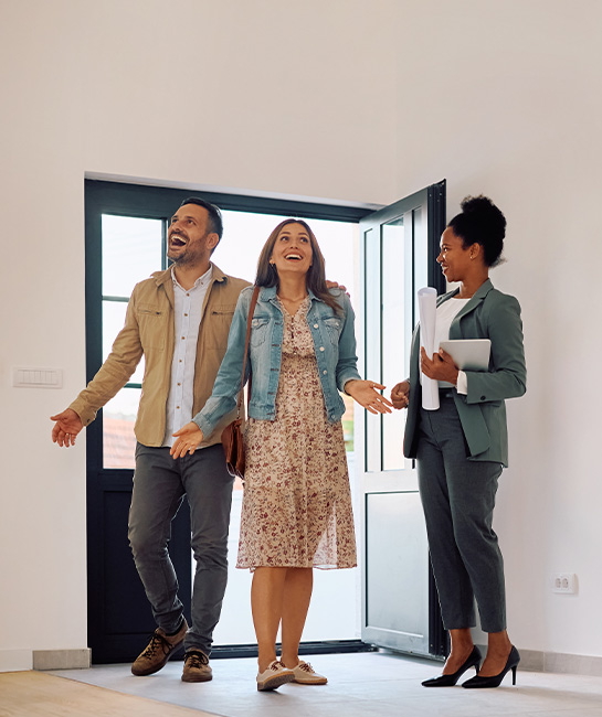 Couple walking into new house looking up at the ceiling smiling