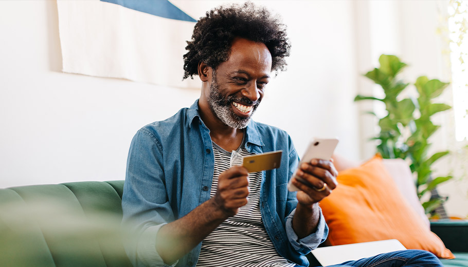 Older man online shopping with his credit card from his couch