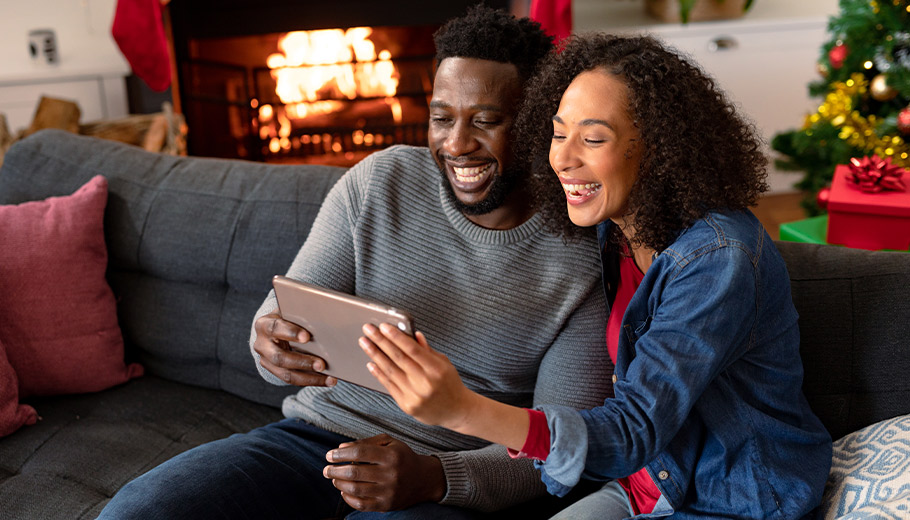 Couple looking at tablet smiling with fireplace in the background