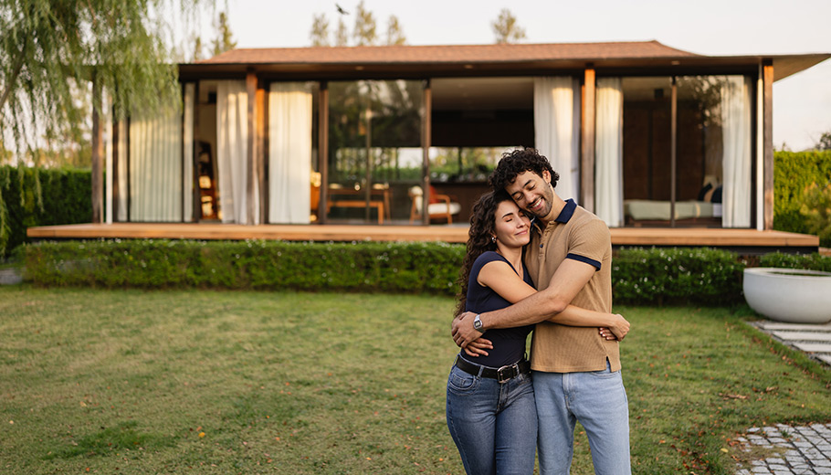 Young couple hugging in front of their home