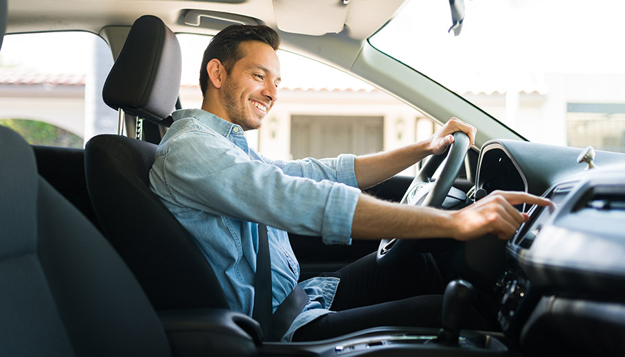 Man in new car pushing buttons on the dash smiling